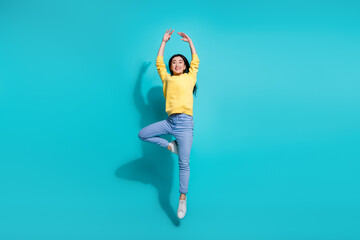 Full length photo of dreamy shiny woman wear yellow pullover dancing jumping high isolated teal...