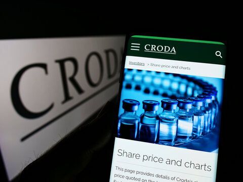Stuttgart, Germany - 05-29-2022: Person holding cellphone with webpage of chamicals company Croda International plc on screen in front of logo. Focus on center of phone display.