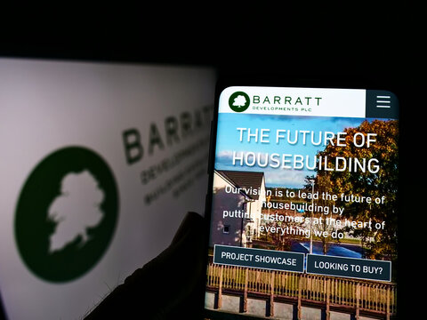 Stuttgart, Germany - 05-29-2022: Person holding cellphone with website of property company Barratt Developments plc on screen in front of logo. Focus on center of phone display.