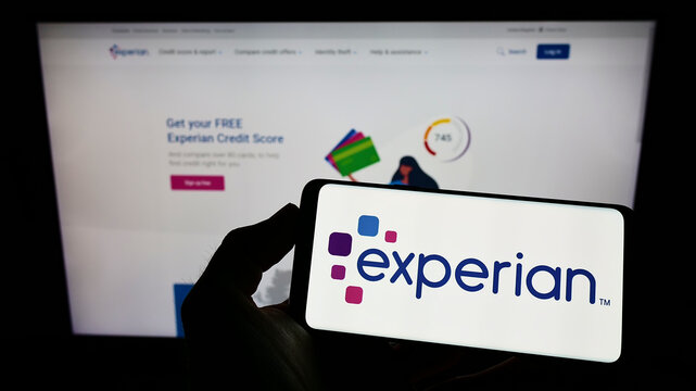 Stuttgart, Germany - 05-29-2022: Person holding cellphone with logo of credit reporting company Experian plc on screen in front of business webpage. Focus on phone display.