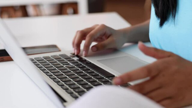 Asian young teenage woman use and typing on laptop computer at library of school. University Library education and Student Learning concept.