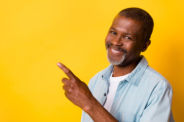 Photo of cheerful friendly man direct finger empty space offer promotion isolated on yellow color...