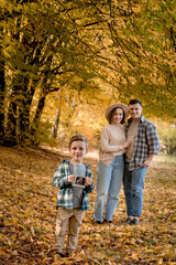 Fototapeta premium Happy family of a man with a woman and surprised son holding an ultrasound pregnancy picture. Autumn photo shoot of a family waiting to be replenished