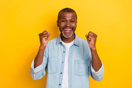 Photo of astonished successful person raise fists shout yes isolated on yellow color background