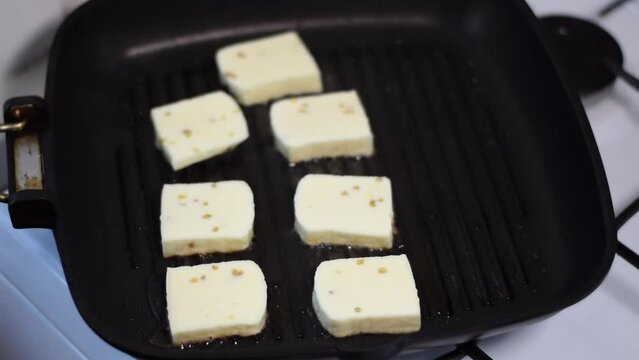 Grilling halloumi cheese on grill pan in the kitchen. Zoom in