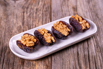 Walnut-stuffed dates on a wood floor. Close-up. Arabian luxury for special occasions such as Ramadan and Eid holidays. local name cevizli hurma
