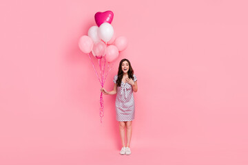 Photo of adorable impressed woman wear white dress arm chest holding air balls isolated pink color background