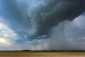Storm clouds over field, downburst of rain, dangerous storm
