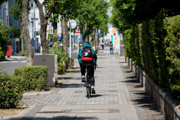 Fototapeta na wymiar 夏の都市の町で自転車を乗っている女性の姿