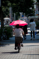 夏の町で日傘を持って自転車を乗っている中高年女性の姿