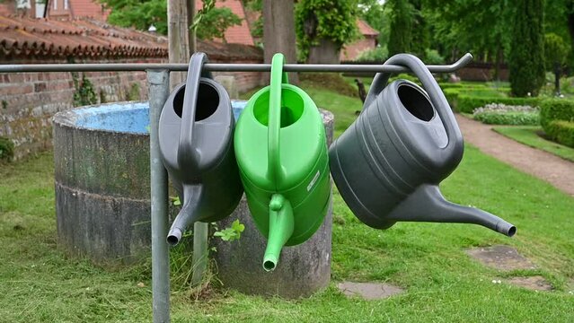 Gie&szlig;kannen wackelnd im Wind auf Friedhof