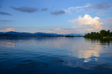 Morning sunrise sky reflects on the surface of a calm lake. Serene nature landscape in lagoon. Tranquil water surface at dusk for relaxation background.