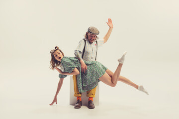 Studio shot of young man and girl in vintage retro style outfits psoing isolated on white...