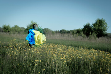The boy runs across the field with the flag of Ukraine