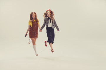 Pretty young girls in retro 80s, 90s fashion style, outfits isolated over white studio background. Concept of eras comparison, beauty, fashion and youth.