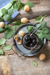 Handmade jam made from green fresh walnuts on a wooden background. Organic walnut jam, healthy food. View from above. Copy space.