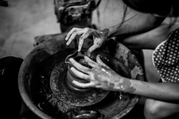 Black and white photo. Tourists learning clay molding in pottery making at Koh Kret, Thailand.