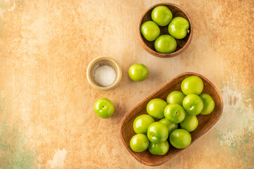 top view ripe green plum fruits served with salt on table
