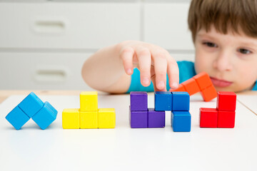 Wooden colorful blocks similar to popular ‎tile-matching puzzle game. Boy matching figures to create new shapes. Montessori type logical game for kids. Brain exercise for preschoolers.