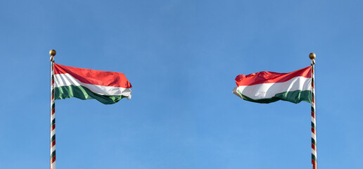 Hungarian flag or flag of Hungary waving against blue sky, panoramic view.