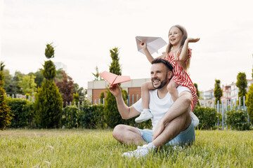 happy father and daughter with paper airplane outdoor
