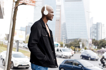 man with black skin listening to the music with headphones outdoor