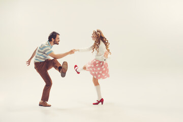 Young man and woman in vintage retro style outfits dancing social dance isolated on white...