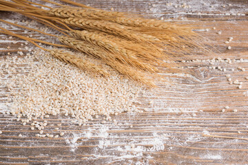 wheat ears with wheat grains and the powder scattered on the wooden table