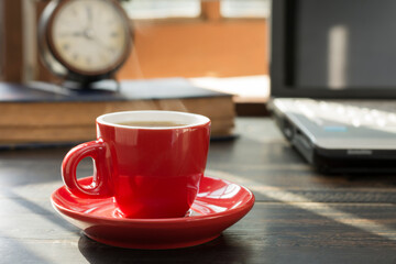 A red coffee cup is placed on the desk. office or at home with a notebook computer keyboard tablet...