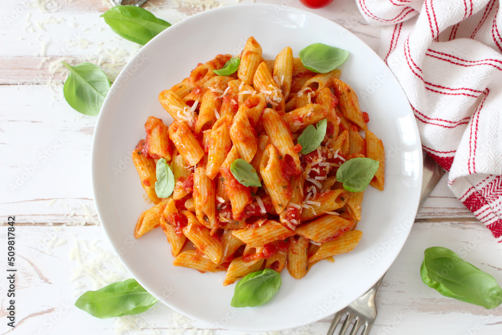 Wall mural penne pasta with tomato sauce, parmesan cheese and pasil on wooden table. top view.