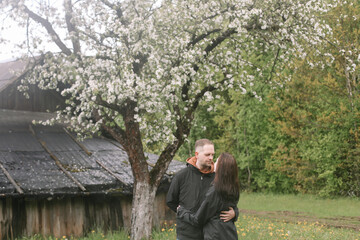 Sensual woman and man in cherry bloom. Couple in love in blossoming garden in spring. Love and romance, relationship, happy family outdoors