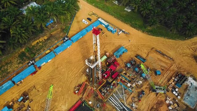 Cinematic Onshore Drilling and Workover Rig structure for oil exploration and exploitation in the middle of jungle surrounded by palm oil trees during sunset time.