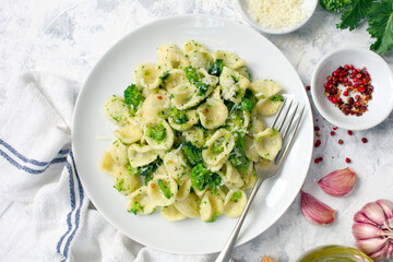Italian pasta - orecchiette with turnip greens on light background. Mediterranean diet. Top view.