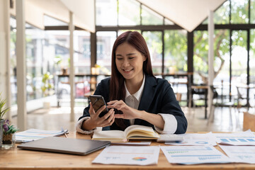 Smiling business asian woman using phone in office. Small business entrepreneur looking at her...