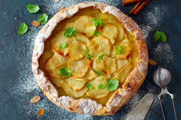 Homemade apple cake with almons and cinnamon on dark background. Top view eith copy space.