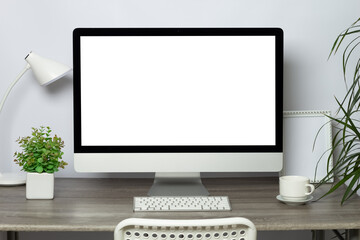 Modern computer with white screen and keyboard on stylish designer desktop. Freelancer workplace. Copy space, mock up.