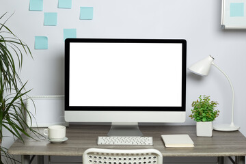 Modern computer with white screen and keyboard on stylish designer desktop. Freelancer workplace. Copy space, mock up.
