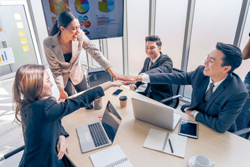 Asian business team show unity with their hands in the office meeting room for assigned tasks that...