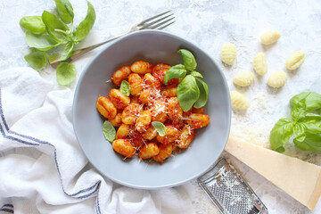 Italian homemade gnocchi with tomato sauce on light background. Top view with copy space.