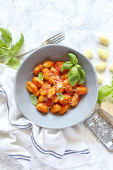 Italian homemade gnocchi with tomato sauce on light background. Top view with copy space.