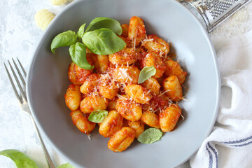 Italian homemade gnocchi with tomato sauce on light background. Top view with copy space.