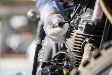 Mechanic check motorcycle spark plug in workshop garage, Man fixing motorbike in repair shop, Repairing and maintenance concepts