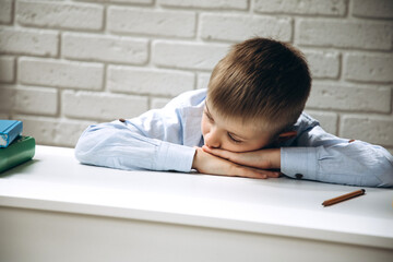 The schoolboy tired and lay down on at the table on the notebook while completing the task for...