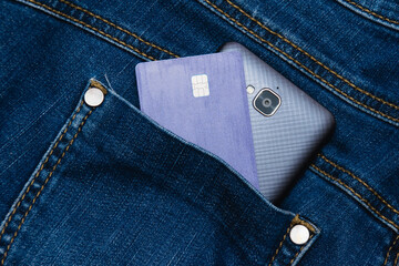 Bank card and smartphone in jeans pocket close up. Business and money concept