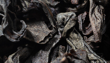 Dried black tea leaves as background.