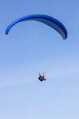 One paraglider flies in the clear sky