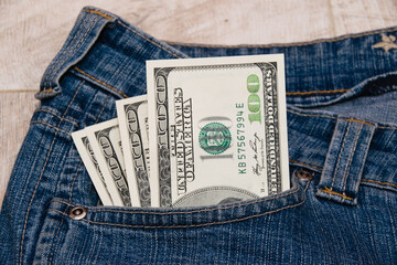 Dollars in the pocket of blue denim pants close up