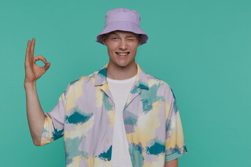 Indoor portrait of young blonde man posing over beige background looking into camera with shocked,horrified facial expression