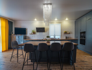 Interior of modern kitchen in blue with yellow accents and wooden floor with large table in middle...