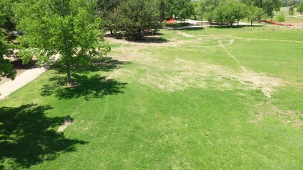 A rising drone shot of a flag marker placed on the lawn of a public park.